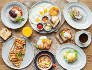 A table full of brunch foods like waffles and eggs.